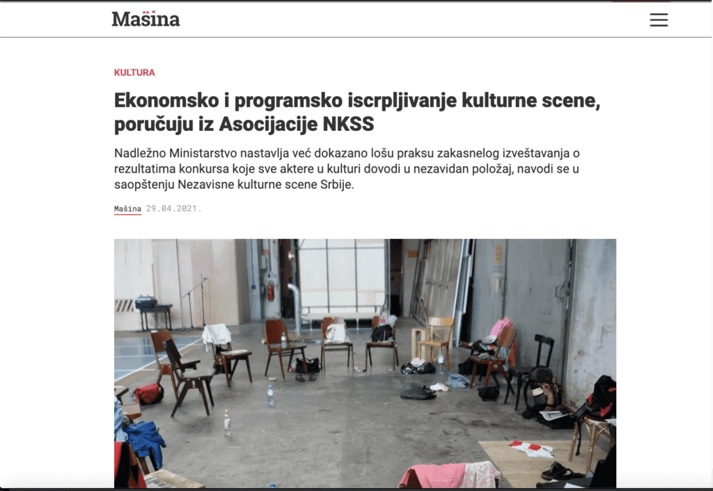 Велика, оскудно намештена соба са разбацаним столицама, столовима, торбама и папирима одражава дух колективне уметности. Неуредан простор, ружичасто ћебе у углу и уметничка дела на белим зидовима изазивају осећај солидарности и креативног активизма.